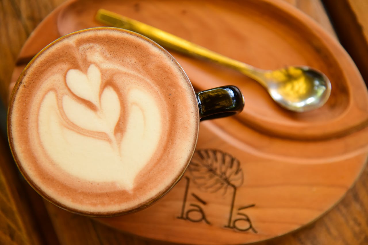 A beautifully crafted latte art design featuring a heart shape in a coffee cup on a wooden tray.