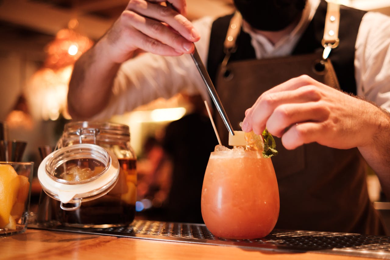A bartender skillfully preparing a refreshing fruit cocktail with precision.